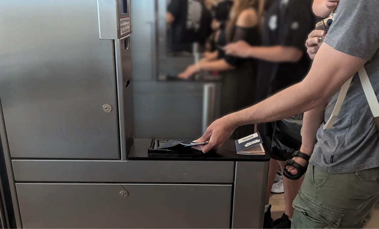A traveler placing a passport on the kiosk scanner