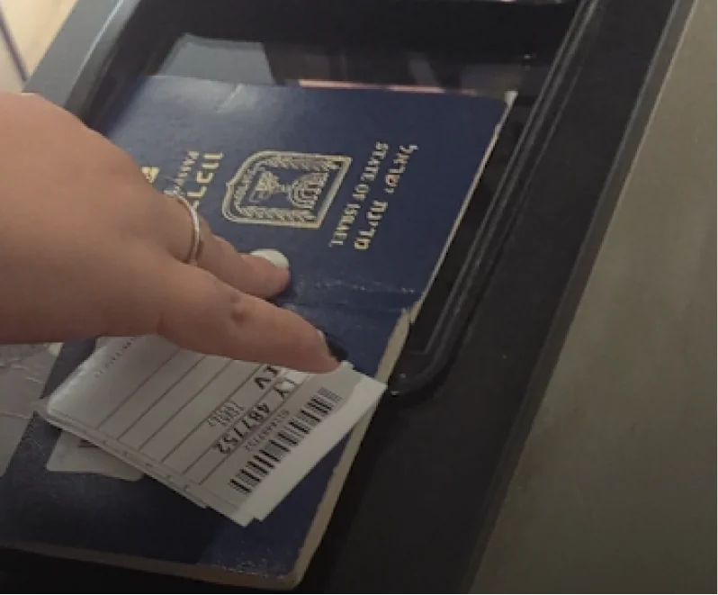 A hand pressing an Israeli passport onto the scanner